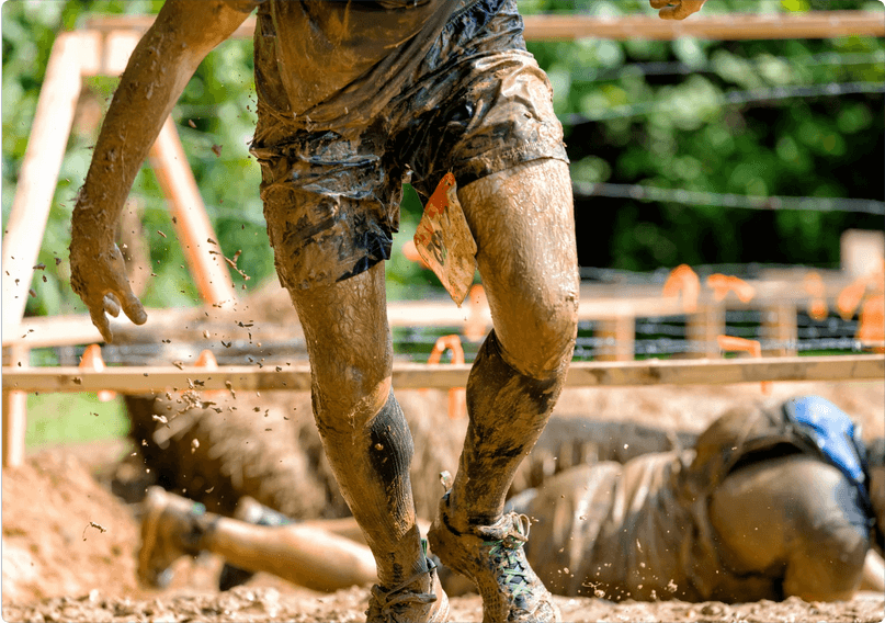 Man running through muddy obstacle course race