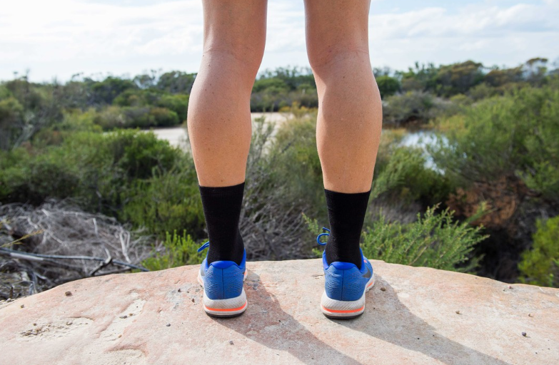 person standing on rock wearing blue socks and black double layer crew socks