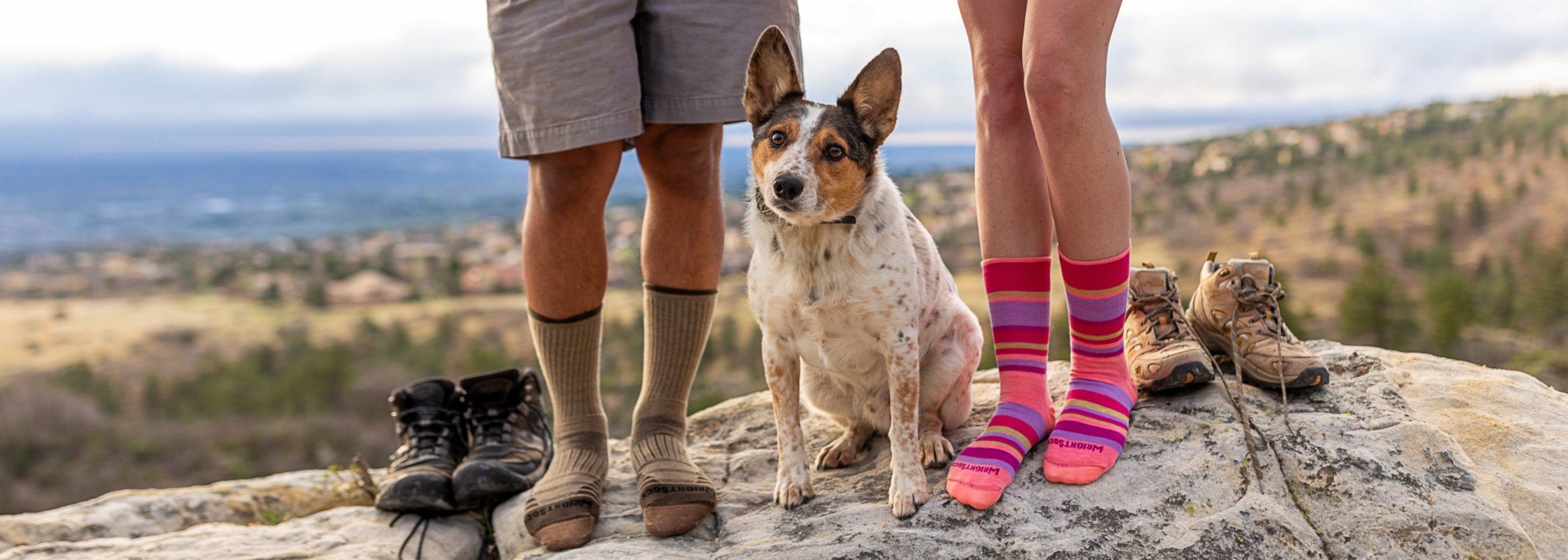 two people wearing hiking socks in mountains with their dog